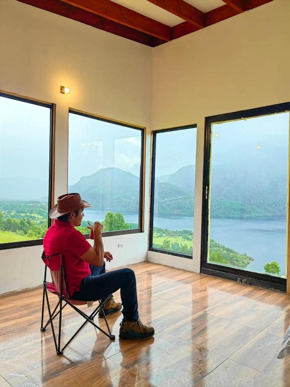 a man sitting in a chair looking out of windows at Cabaña7 in Neltume