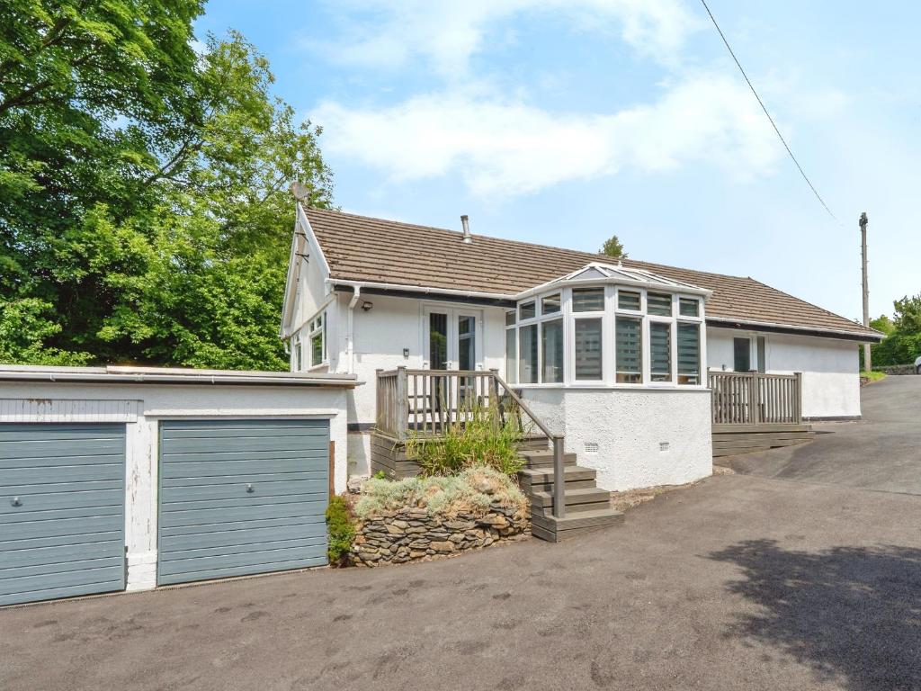 a white house with two garage doors and a driveway at Mylnebeck Lodge in Windermere