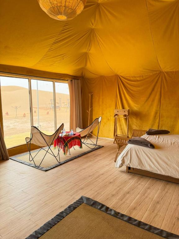 a bedroom with a tent with a bed and chairs at Le Pacha Luxury Desert Camp - Mhamid Sahara Activities in Mhamid