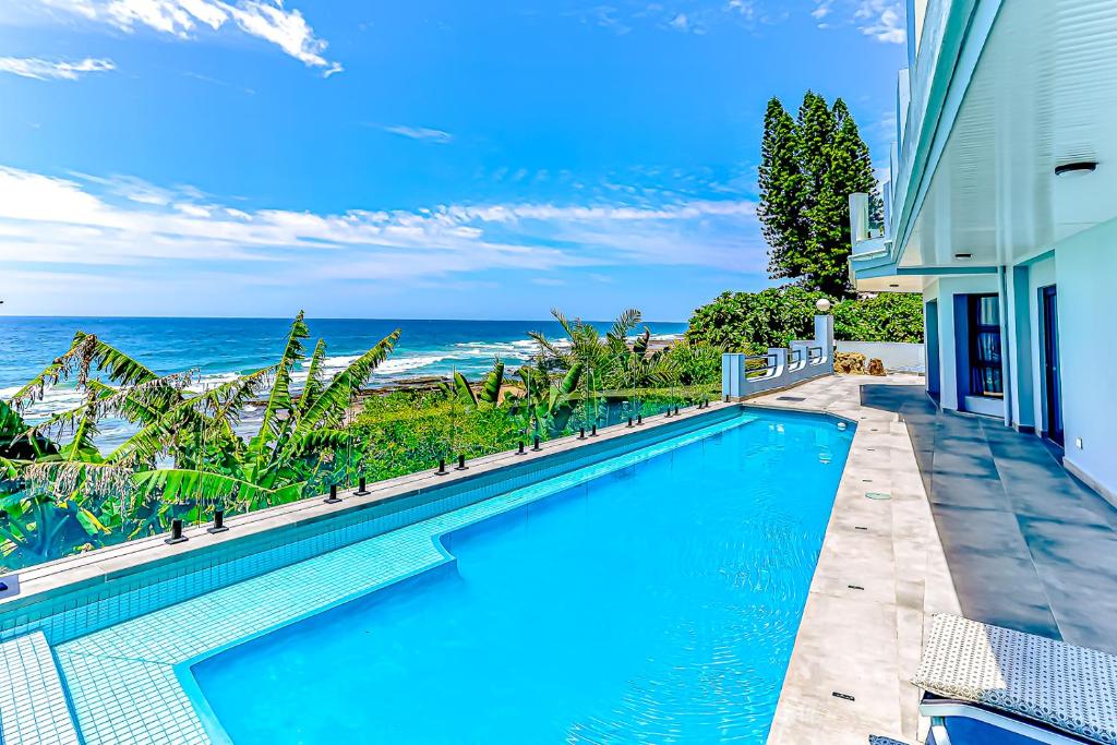 a swimming pool with the ocean in the background at Villa Belle Mere Boutique Hotel in Sheffield Beach