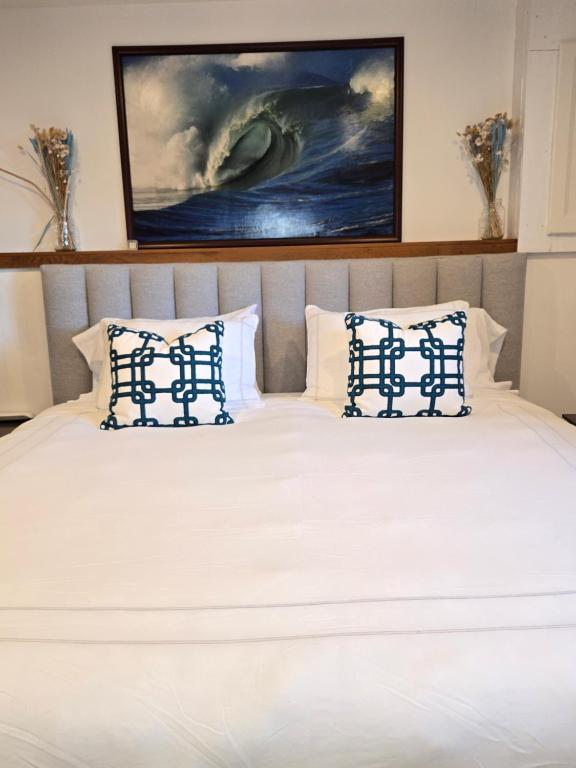 a bed with white sheets and blue pillows at Rustic Guest Suite in Ucluelet