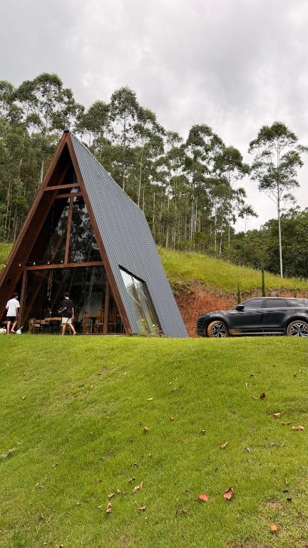 a car parked in front of a triangular house at Cabana de Vidro - Canelinha in Canelinha