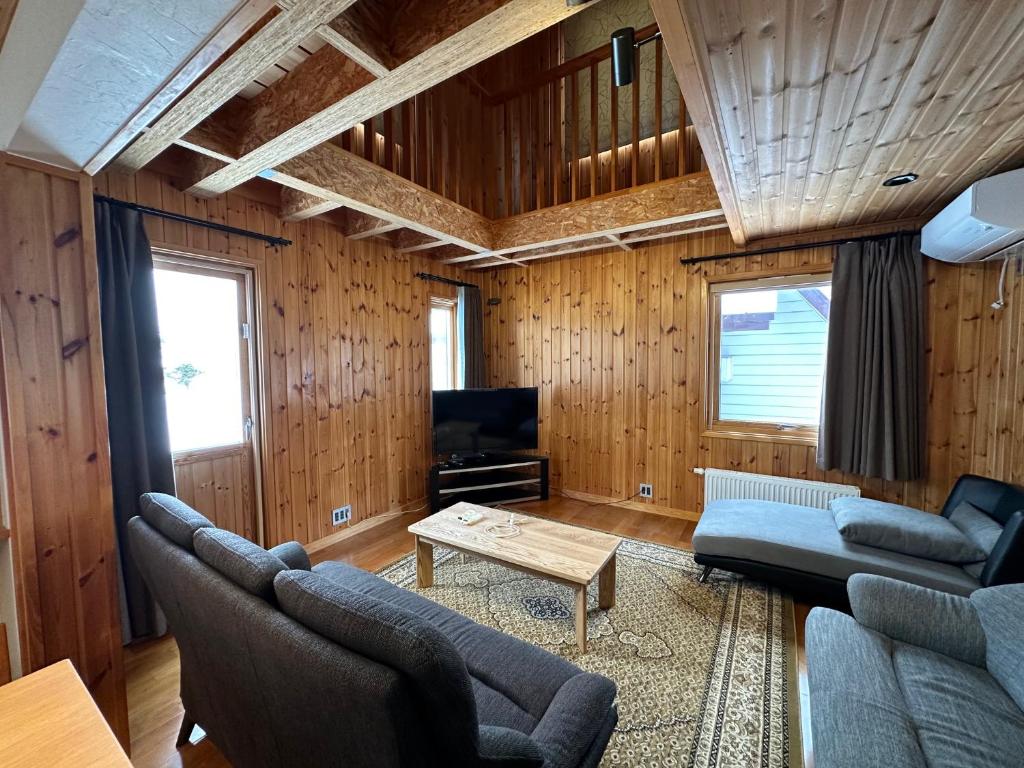 a living room with wooden walls and a couch and a table at Chalet Yutaka in Furano