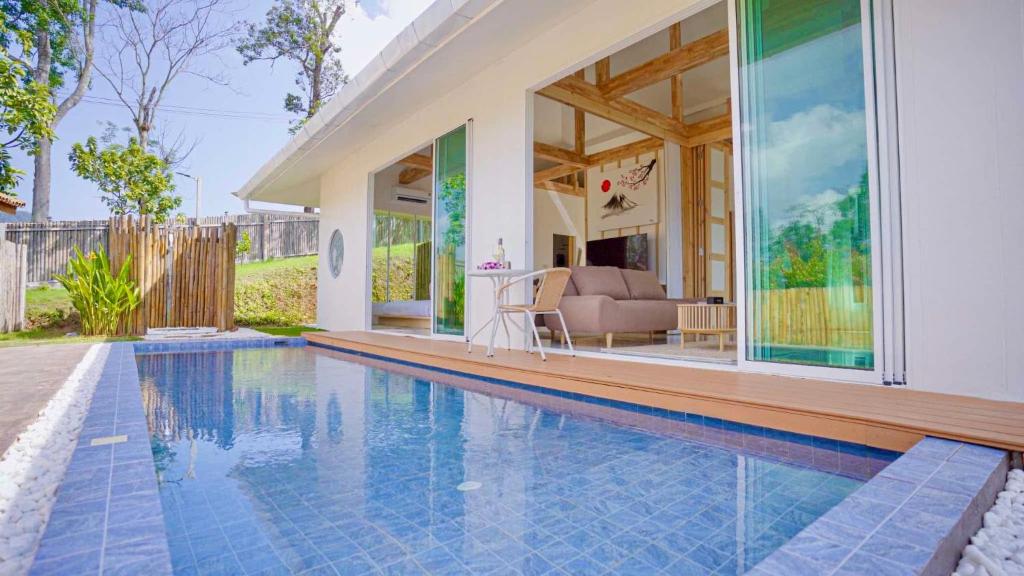 a swimming pool in front of a house at Japanese house PhuSaimorkVilla in Ban Kai Noi