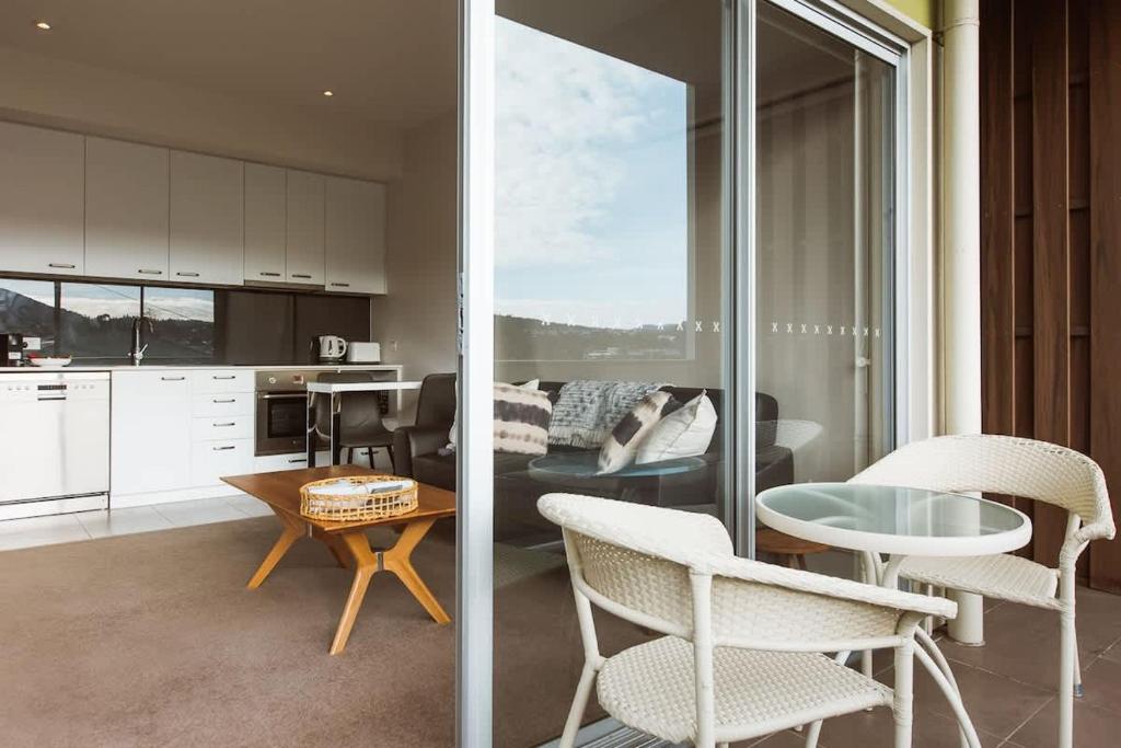 a living room with chairs and a table and a kitchen at Montage Apartment + Views + Location + Car Parking in Bellerive