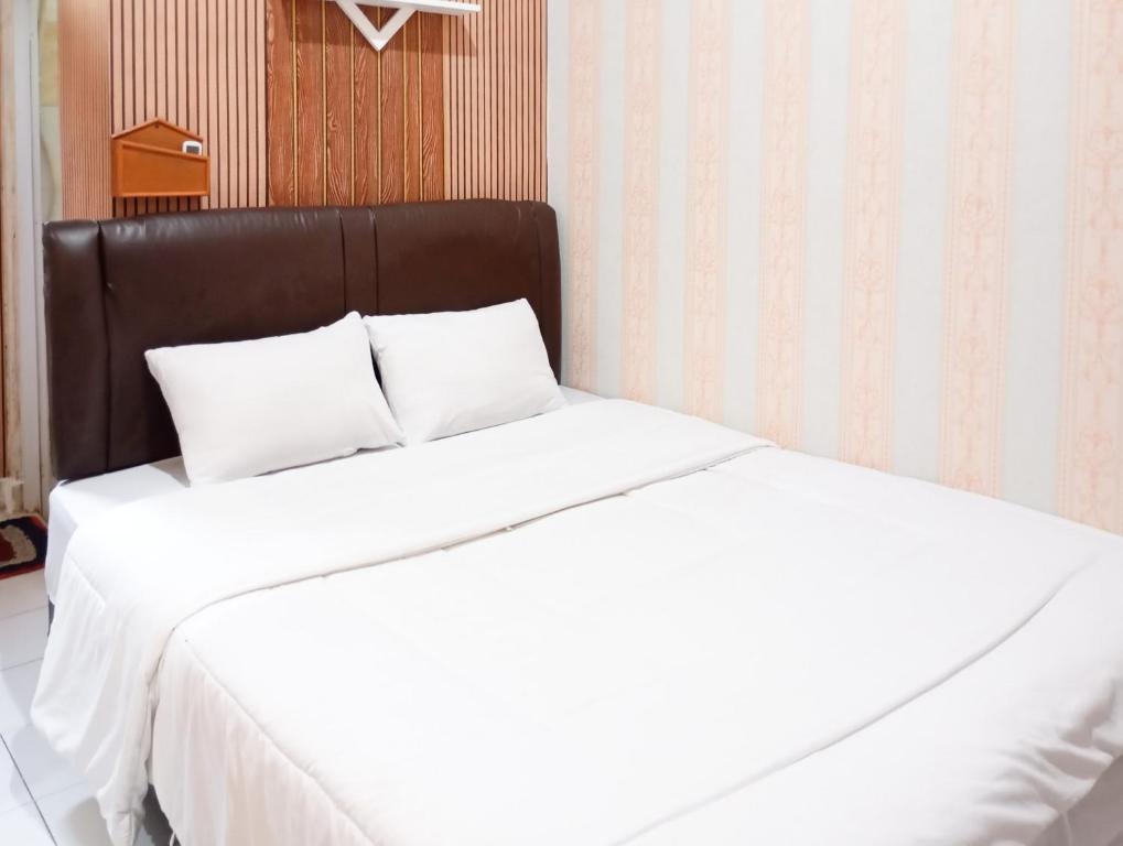 a white bed with a black headboard in a room at Roemah Djogja Inn Seturan Raya RedPartner in Seturan