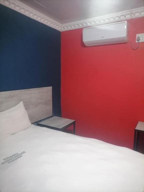 a bedroom with a white bed and a red wall at Ndamu guesthouse in Vosburg