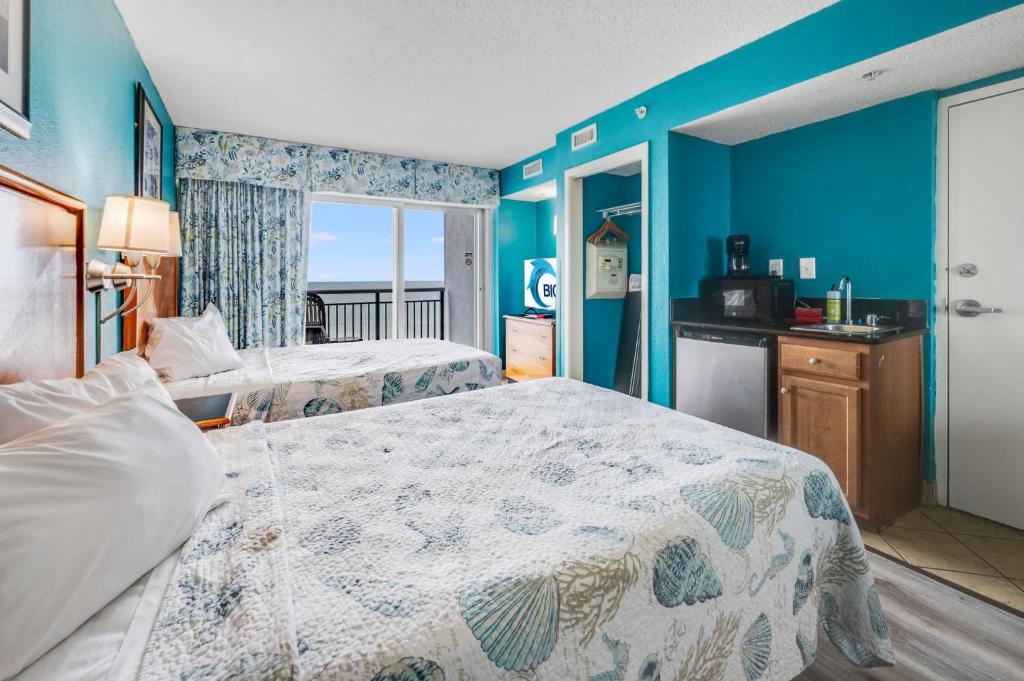 a bedroom with two beds and a blue wall at Oceanfront,Heated Pools,Boardwalk, Location,Views! in Myrtle Beach