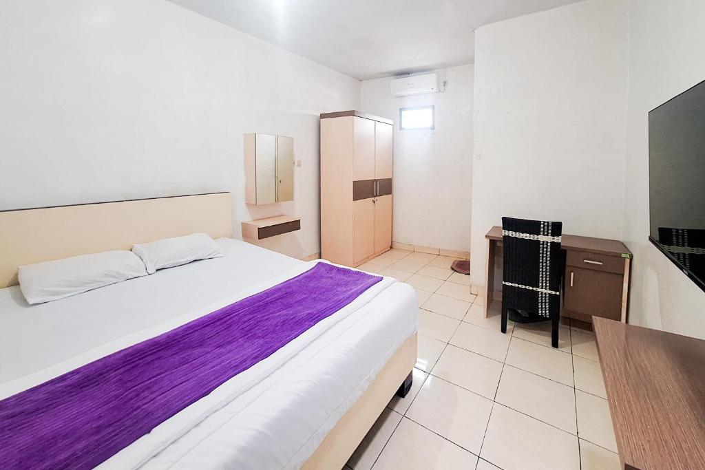 a bedroom with a bed and a desk and a television at Villa Citra Syariah RedPartner in Kalibata 1