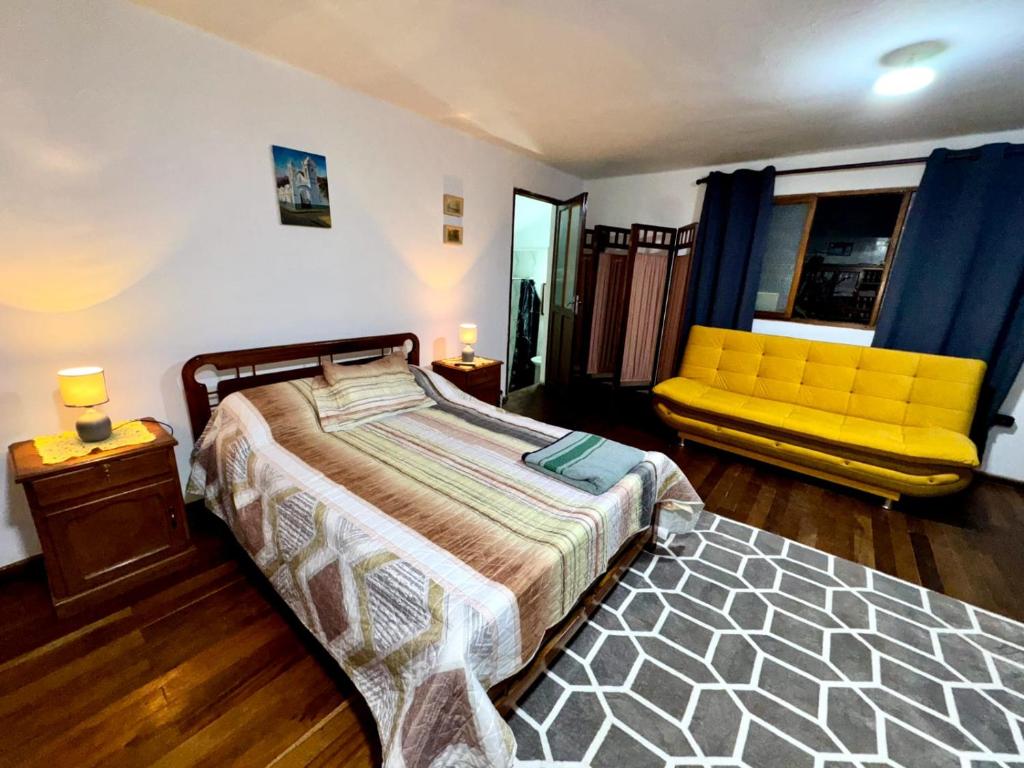 a bedroom with a bed and a yellow couch at Avaroa 350 express in Sucre