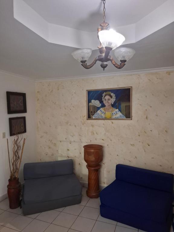 a living room with two blue chairs and a painting at Casa Margarita in Santiago