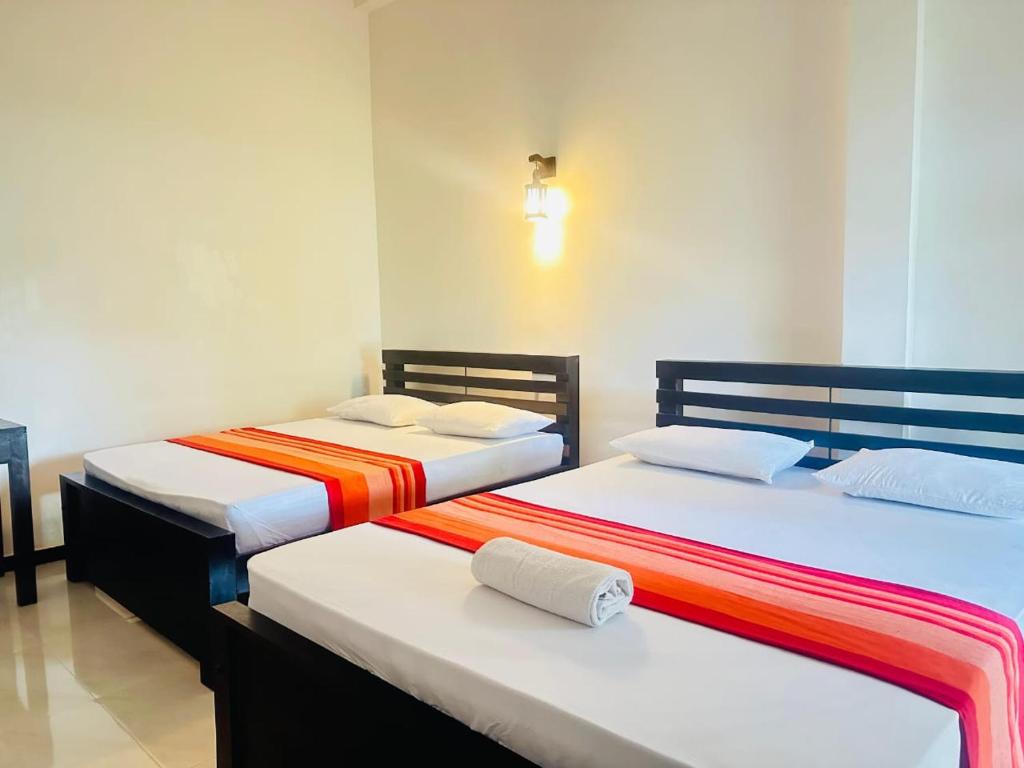 two beds sitting next to each other in a room at Yala Thaman Katharagama in Kataragama