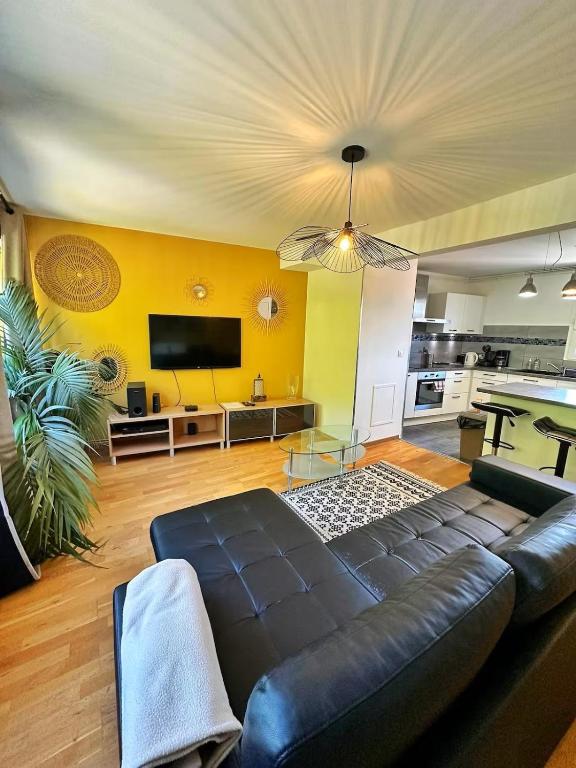 a living room with a black leather couch and a tv at Duplex with Jacuzzi and parking Close to Disney in Lognes