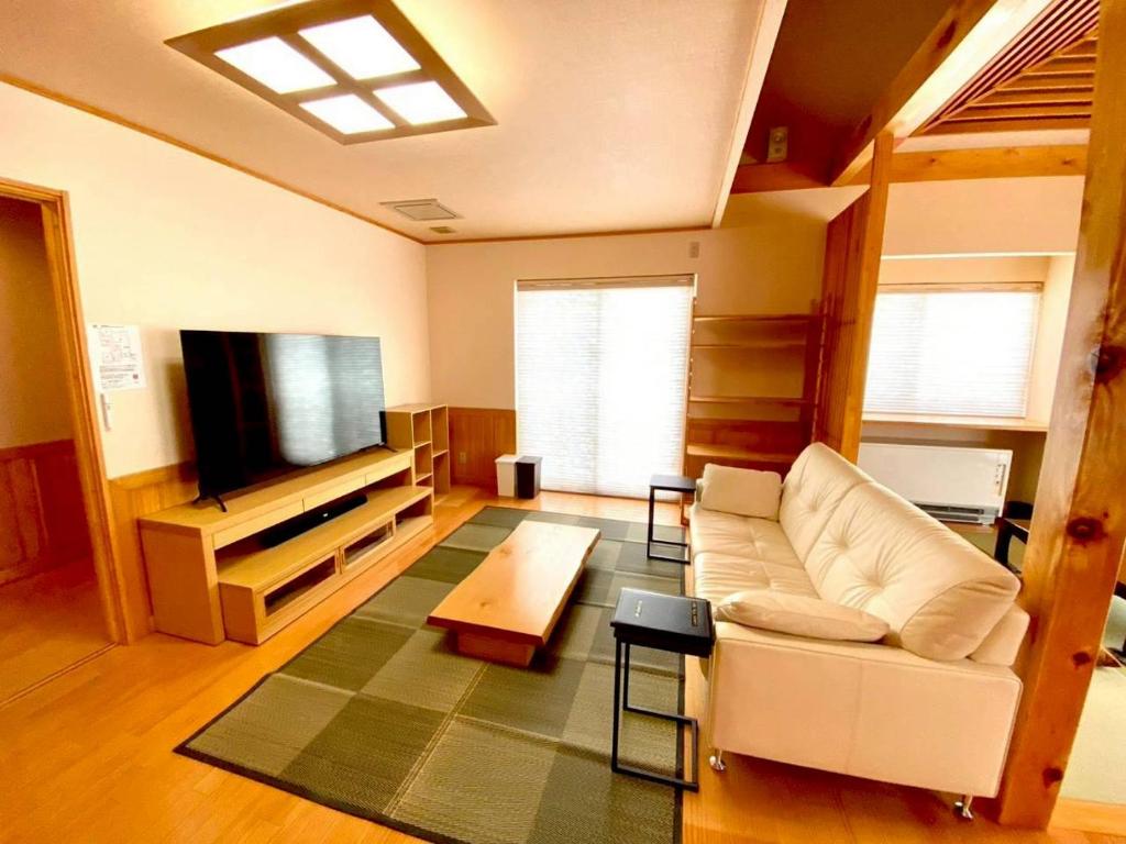 a living room with a white couch and a flat screen tv at Luxury Villa N and N in Aomori