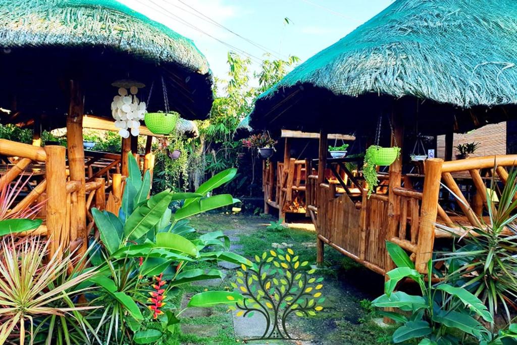 a restaurant with a large straw umbrella and some plants at MJs Garden Hotel Moalboal powered by Cocotel in Moalboal
