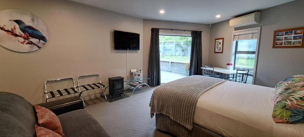 a bedroom with a bed and a television and a living room at Hidden Gem in Oaklands in Napier