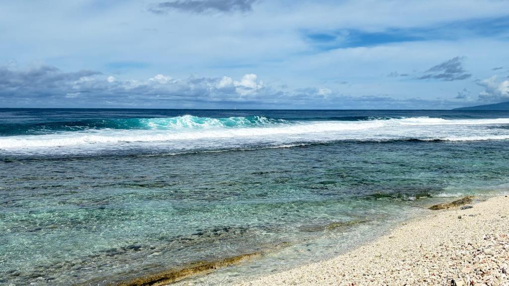 a beach with the ocean and the waves at Moorea Fare Korail in Temae