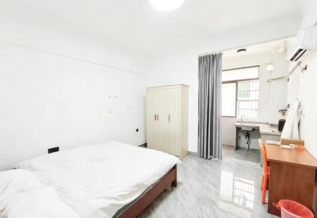 a white bedroom with a bed and a desk at 腾达公寓 in Wanning