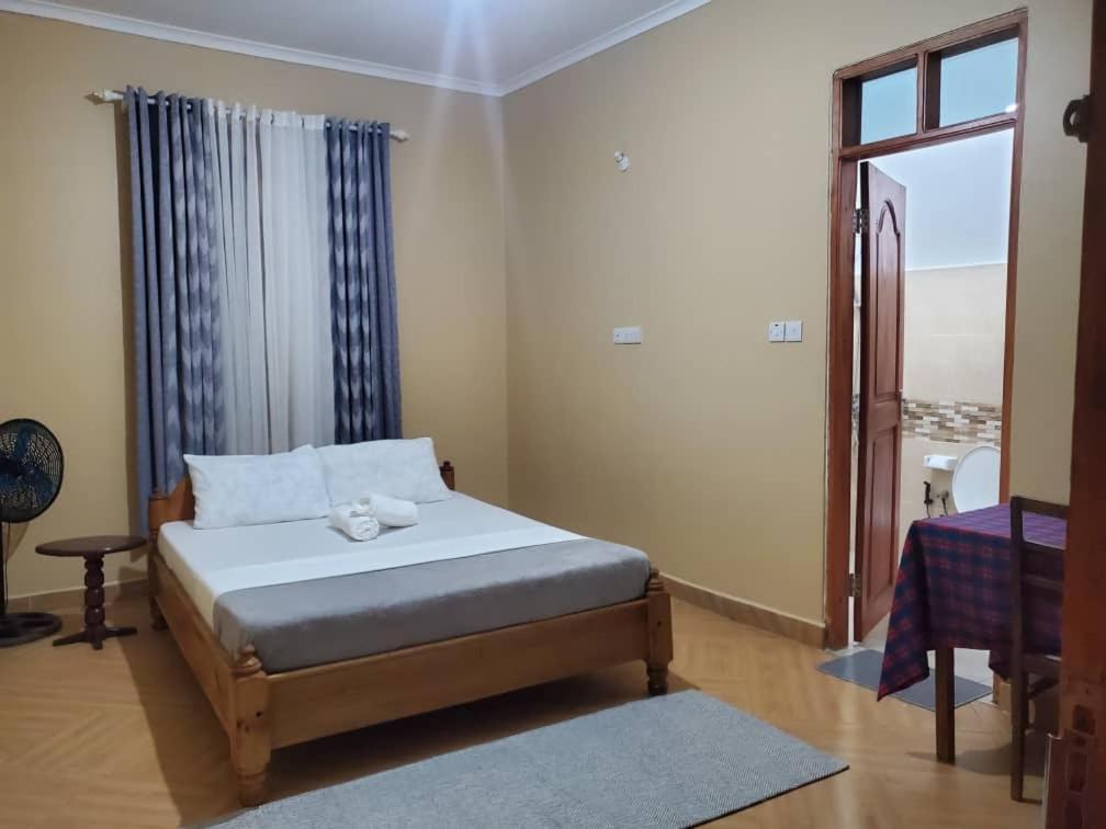 a bedroom with a bed and a window at Shilling Stays in Msaranga