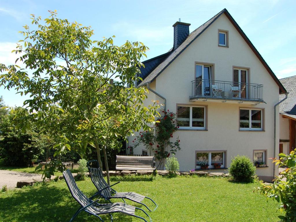 una casa con dos sillas en la hierba frente a ella en Comfortable holiday home Manderscheid with garden, en Manderscheid