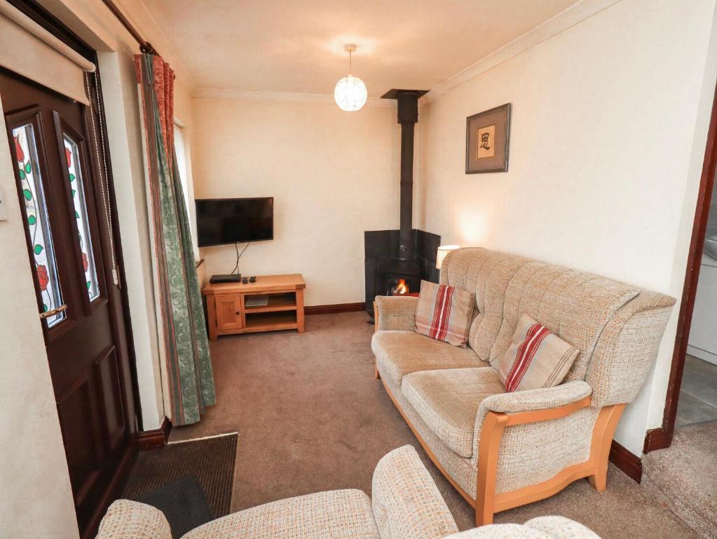 a living room with a couch and a television at Ghyll Bank Bungalow in Staveley