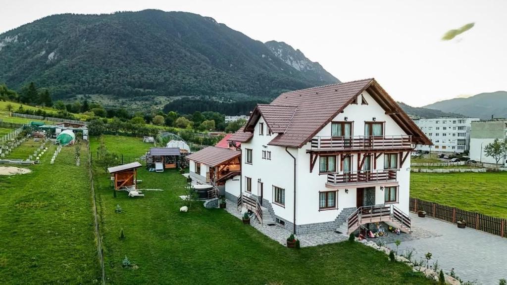 a large white house with a mountain in the background at Popasul Piatra Craiului in Zărneşti