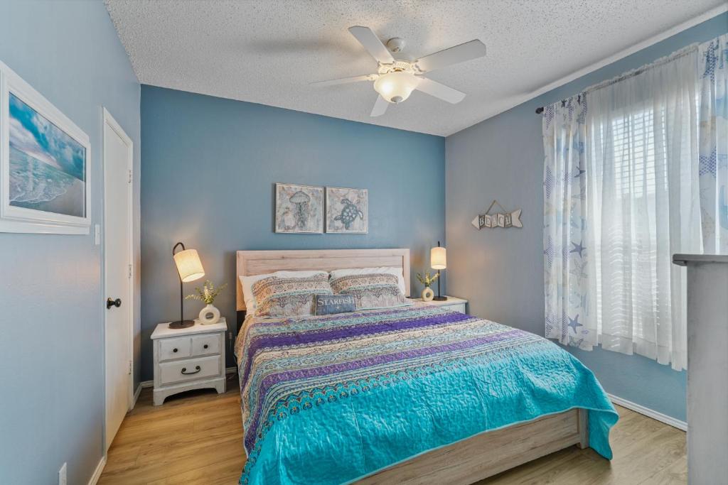 a blue bedroom with a bed and a ceiling fan at Island Palms - 2 min walk to the Beach in Corpus Christi