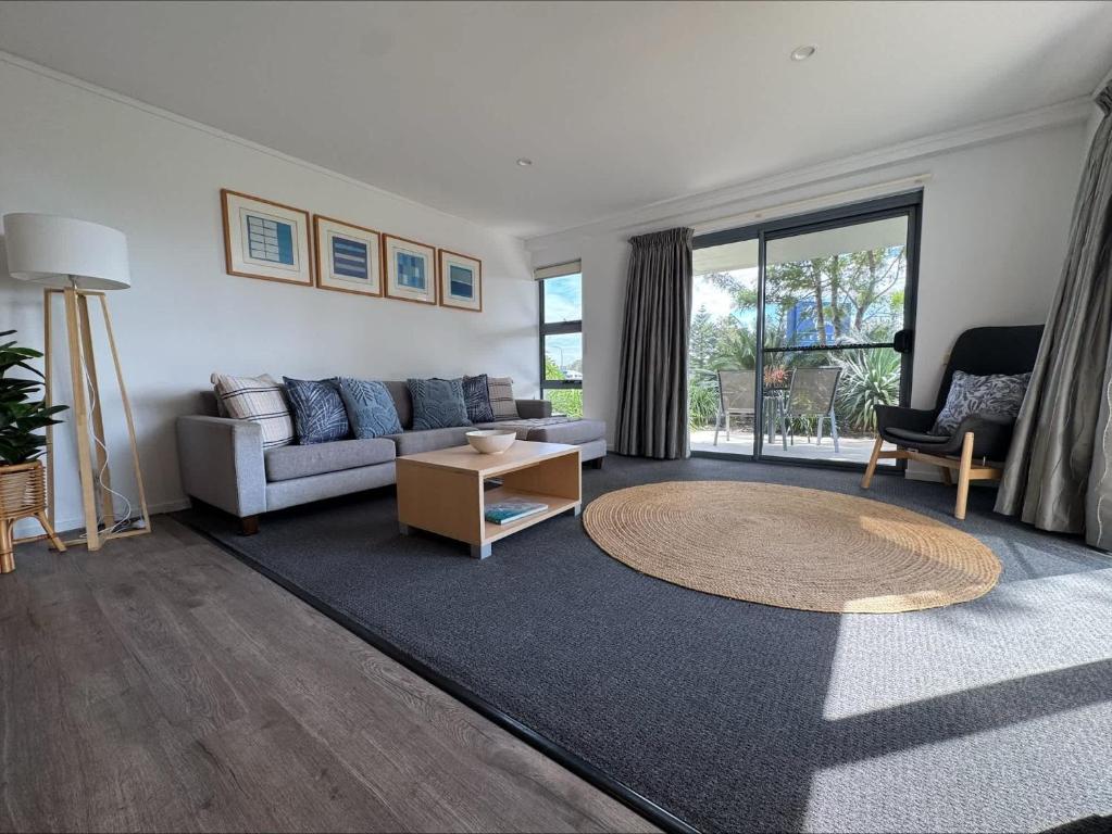 a living room with a couch and a table at Ground Floor Spa Apartment Corrigans Cove in Batehaven