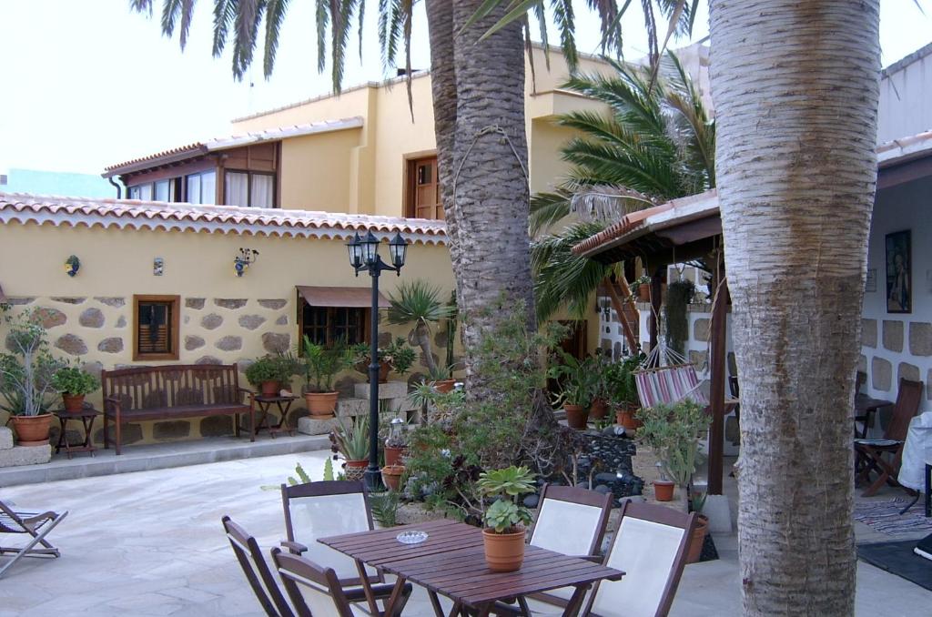 un patio con mesa, sillas y palmeras en Casa Rural El Traspatio en Granadilla de Abona