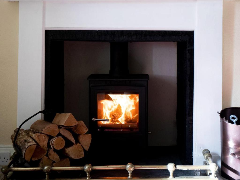 a black fireplace with a fire in it at Mill Cottage-Uk7348 in Dyke