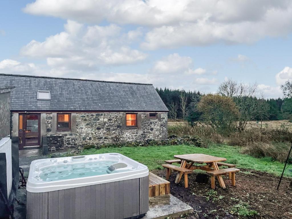a building with a hot tub and a picnic table at Ochiltree Cottage - Uk7781 in Newton Stewart