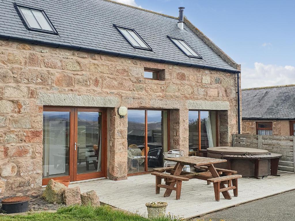 a stone house with a picnic table and a picnic bench at The Stables - Uk7791 in Milton of Auchinhove