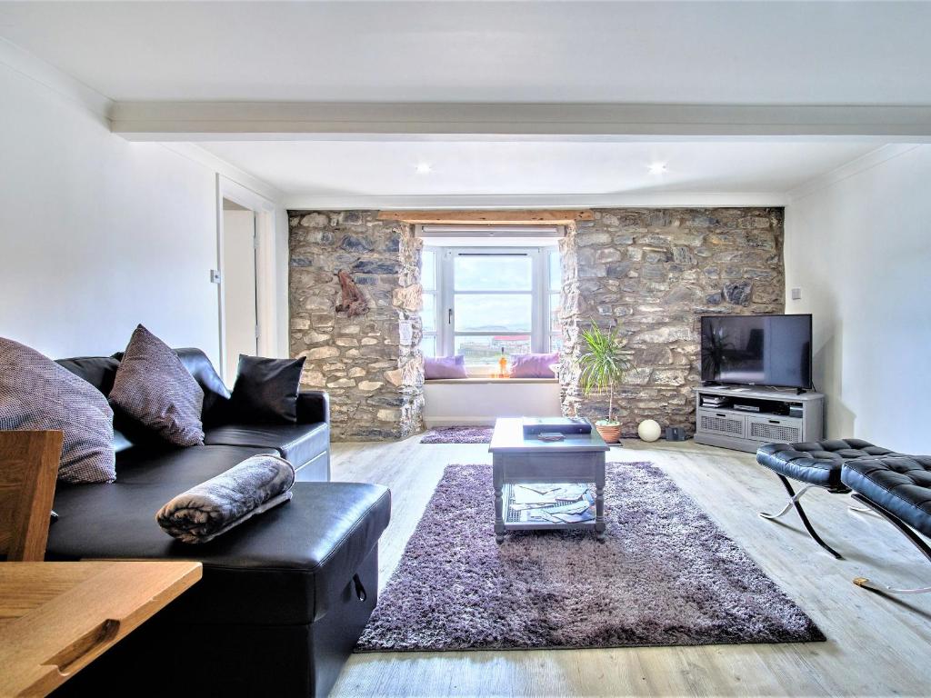 a living room with a black couch and a tv at Imperial Apartment in Oban