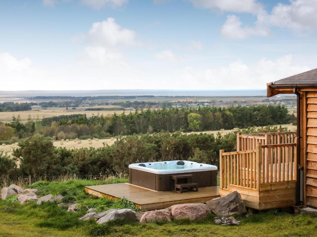 a hot tub on a deck next to a house at Ben Klibreck in Kinloss