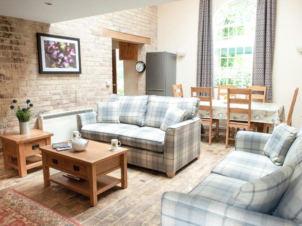 a living room with two couches and a table at Stearn Cottage-17917 in Langham