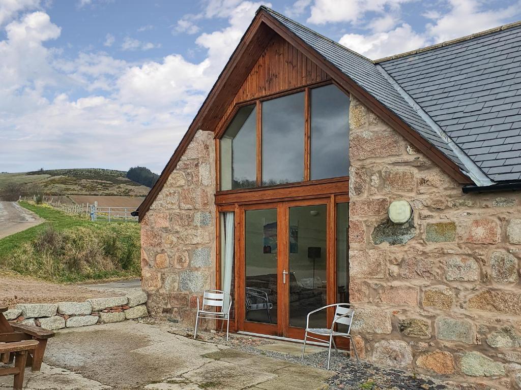 a stone house with two chairs in front of it at The Byre - Uk7790 in Milton of Auchinhove