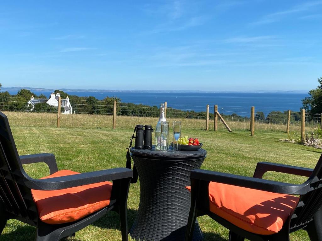 a table with two chairs and a table with wine glasses at Dhunan - Uk7836 in Brodick