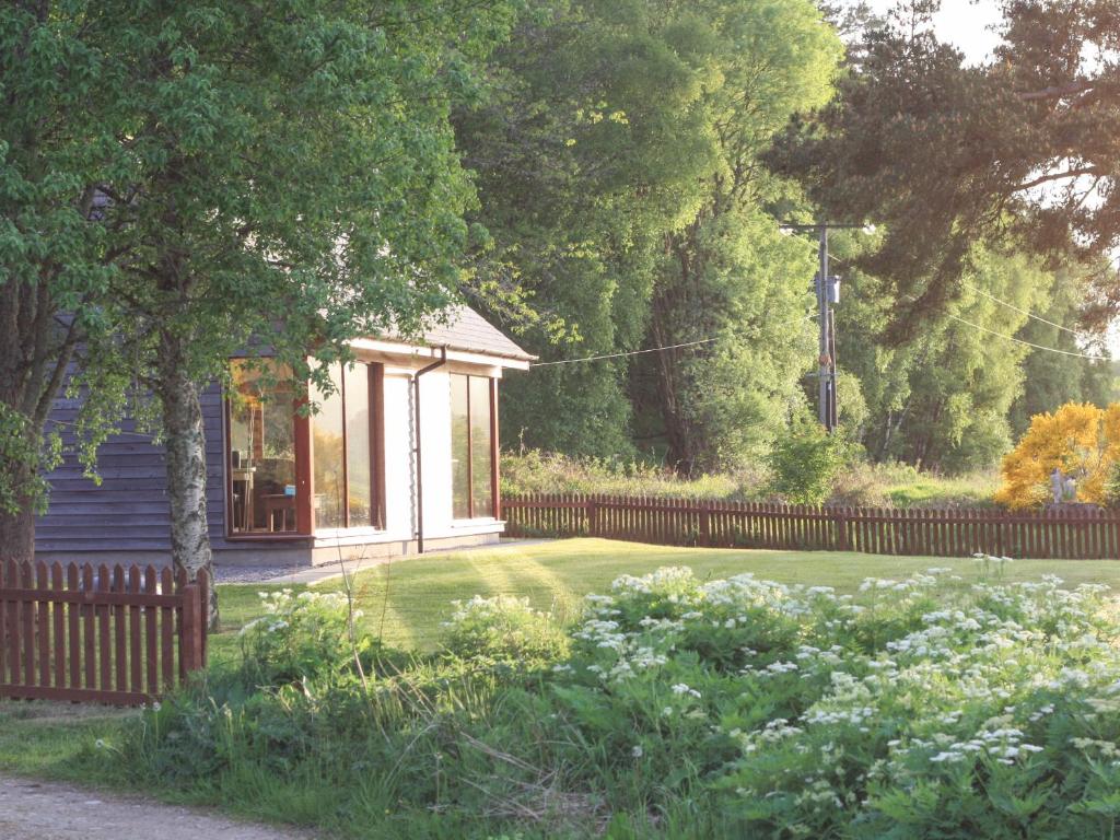 a small house with a fence in a yard at Ford Cottage in Banchory