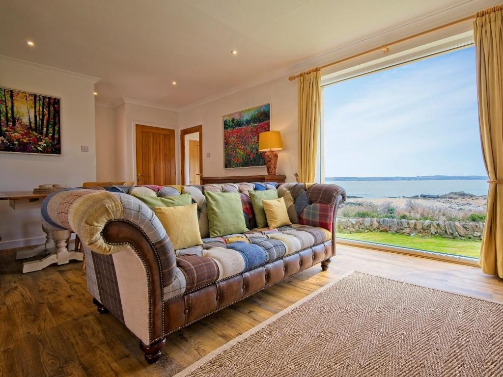 a living room with a couch and a large window at Edenville in Girthon