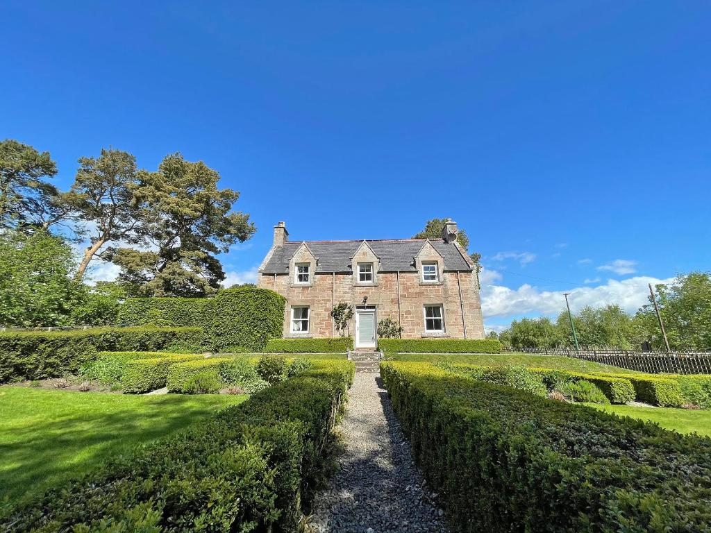 an old house with hedges in front of it at Balloan Cottage-Uk7382 in Dornoch