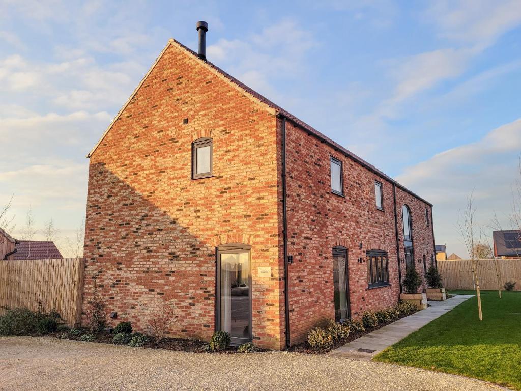 a red brick building with a door in a yard at The Hazels - Ukc4614 in Dunholme