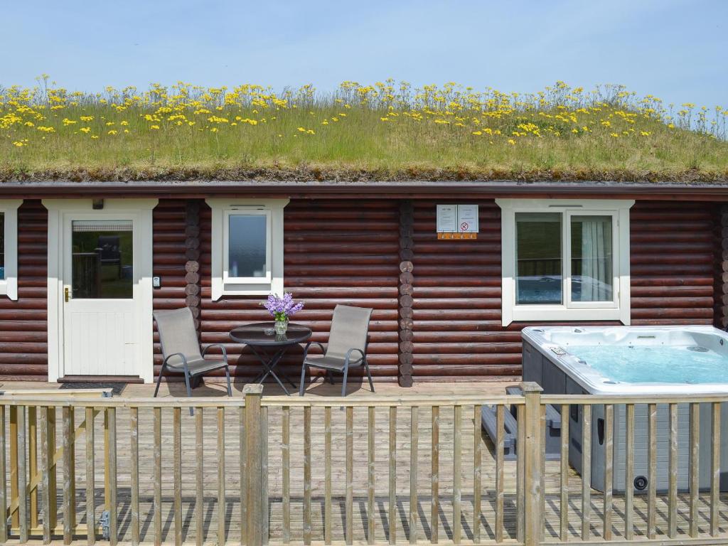 a house with a grass roof with chairs and a hot tub at Kingfisher Lodge- W43170 in Burn