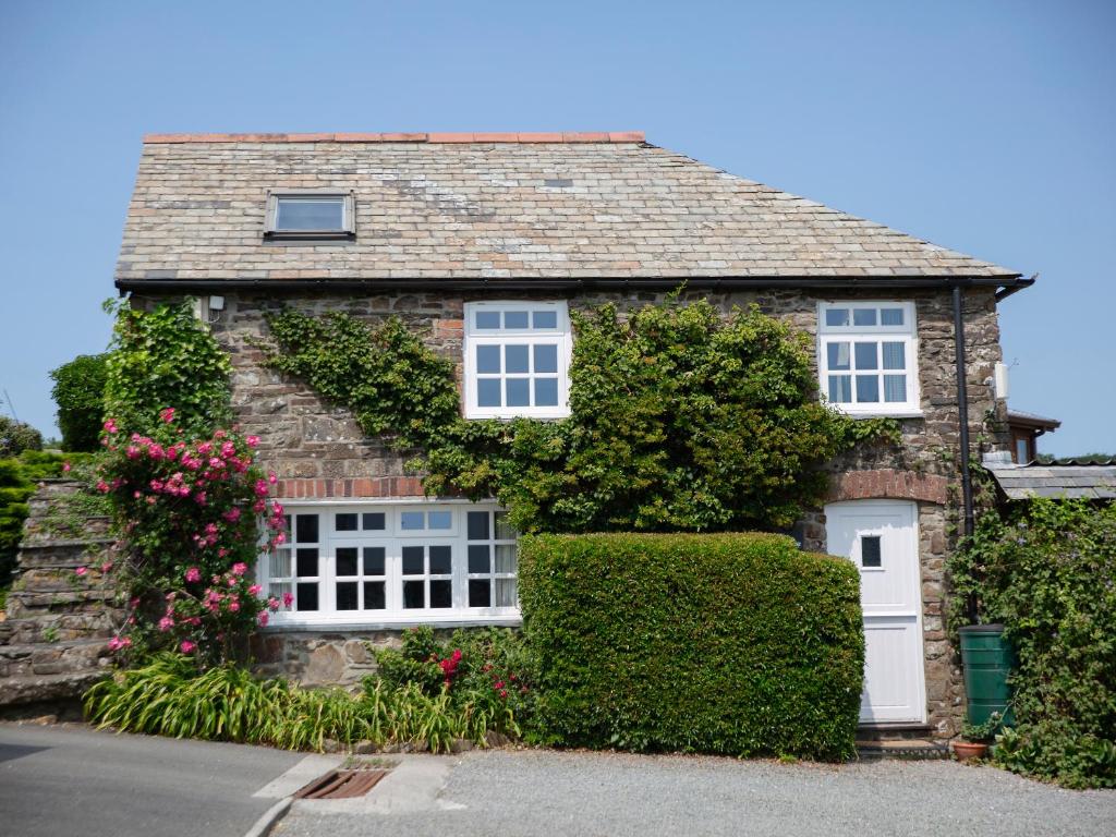 a stone house with flowers and ivy at The Coach House - Ukc4691 in Kilkhampton