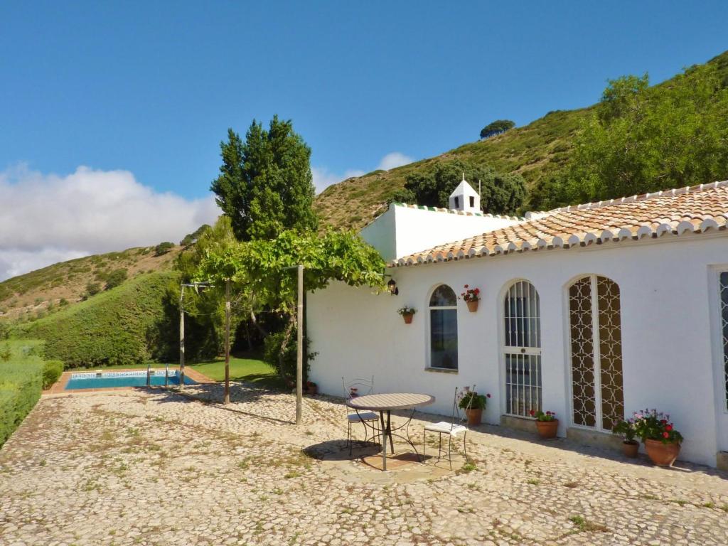 ein weißes Haus mit einem Tisch und Stühlen vor einem Hügel in der Unterkunft Belvilla by OYO Casa Torcalillos in La Joya