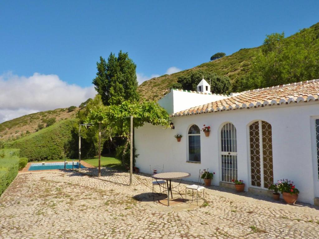 a white house with a table and chairs in front of a hill at Belvilla by OYO Casa Torcalillos in La Joya