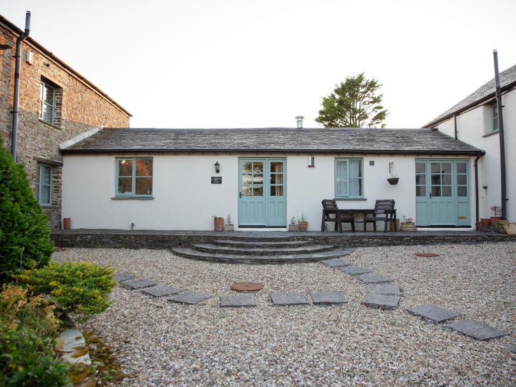 a white house with blue doors and a patio at Honeysuckle Cottage - Ukc4692 in Kilkhampton
