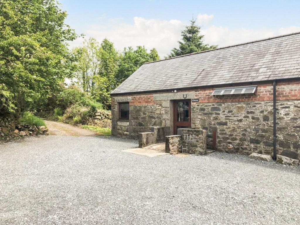 an old stone house with a gravel driveway at Maberry Cottage - Uk7784 in Newton Stewart