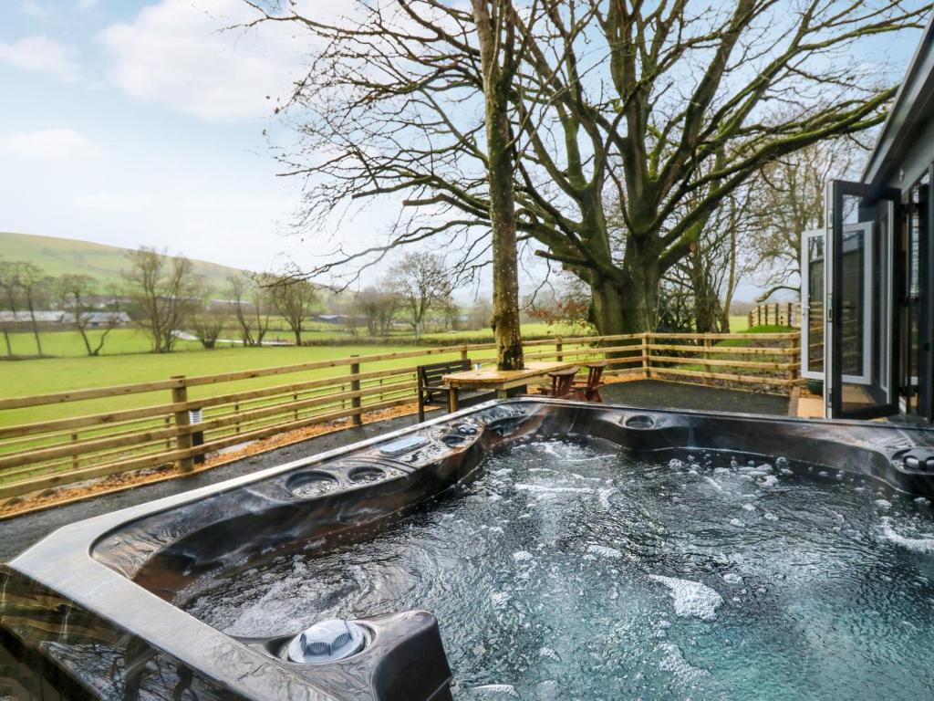 a hot tub with water in it next to a fence at The Foxes Den - Ukc8196 in Dolau