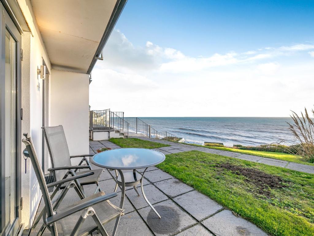a patio with a table and chairs and the ocean at 20 Mount Brioni in Downderry