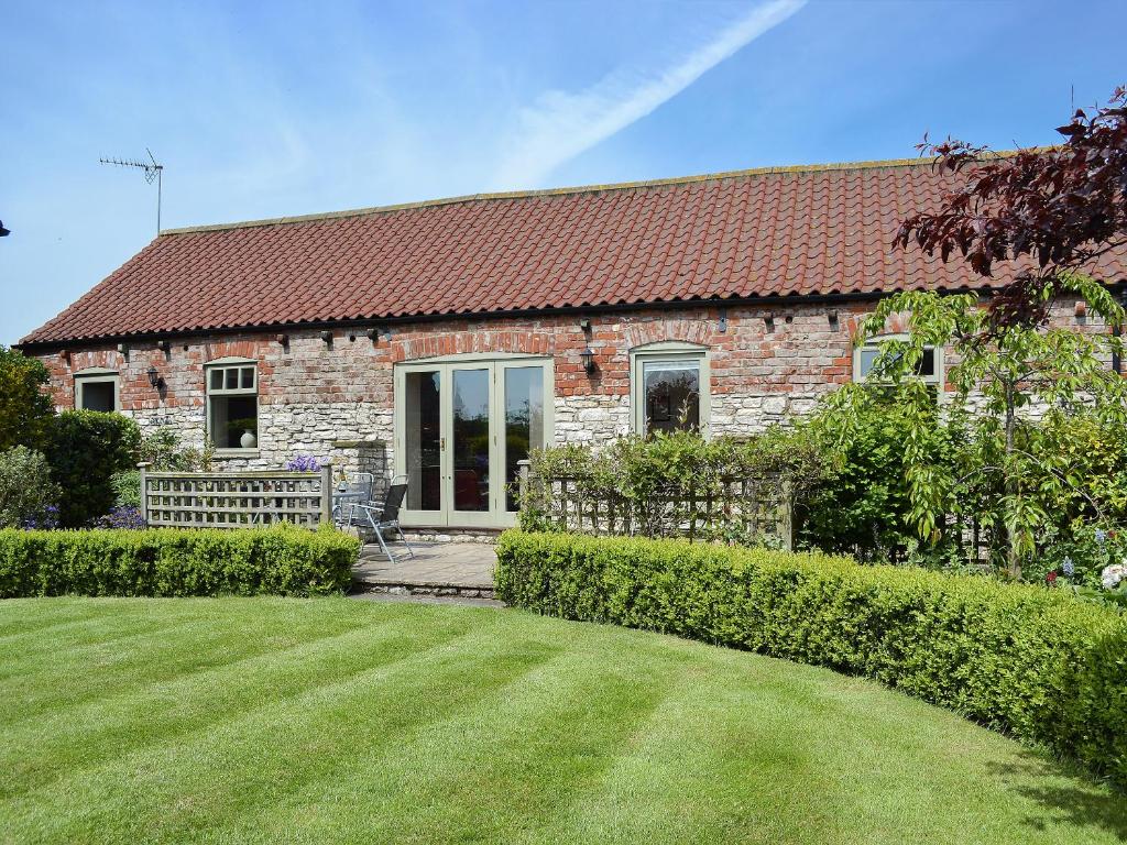 a brick house with a lawn in front of it at Stables Cottage-W42586 in Burn